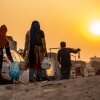 A Rohingya refugee woman walks home, carrying a container of drinking water fetched from a distribution point in Madanpur Khadar Rohingya refugee camp, in New Delhi, India.
