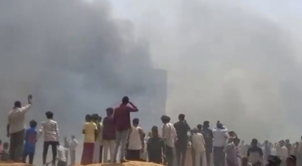 People watch smoke rising after an airplane crashed in Ahmedabad, Gujarat state, India, on Thursday.
