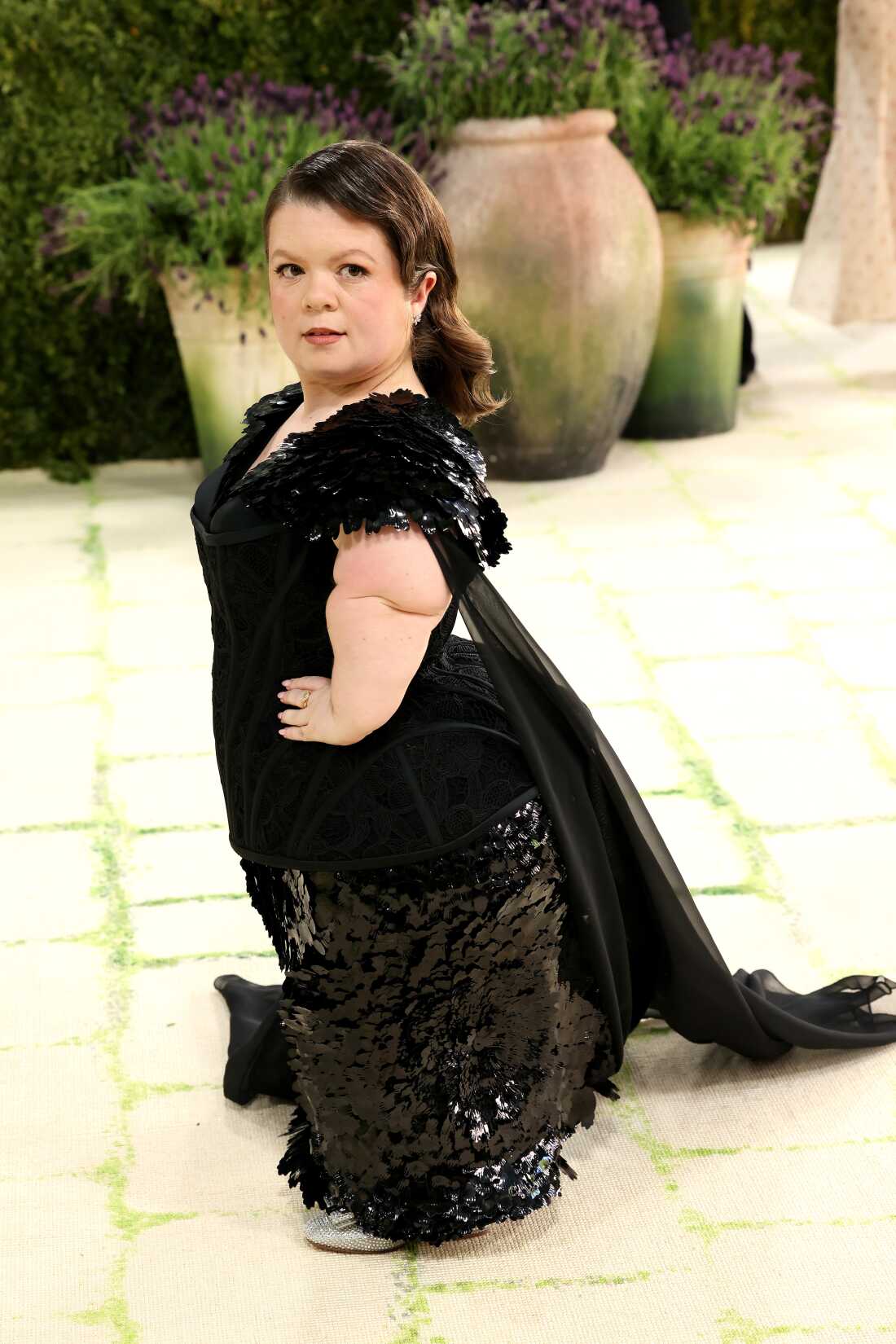 Sinéad Burke attends the 2026 Met Gala. She is wearing a floor-length black gown and train. She is a little person.