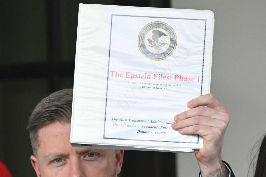 Political commentator Rogan O'Handley, aka DC Draino, holds up the binder titled "The Epstein Files: Phase 1," with the Justice Department seal.