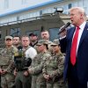 President Trump holds a mic and stands next to National Guard members and federal officers during a visit to the U.S. Park Police Anacostia Operations Facility.