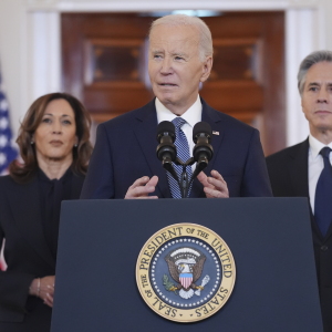 Joe Biden speaks at a White House podium, with Kamala Harris standing behind him at left and Antony Blinken at right.