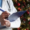 A doctor writes on a clipboard while standing in front of a heavily decorated Christmas tree.