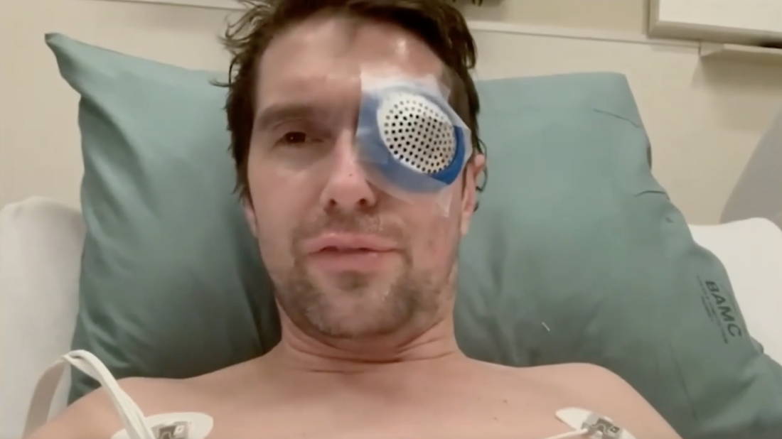 Fox News correspondent Benjamin Hall is in a hospital bed, wearing a large eye patch and with tubes attached to his chest.