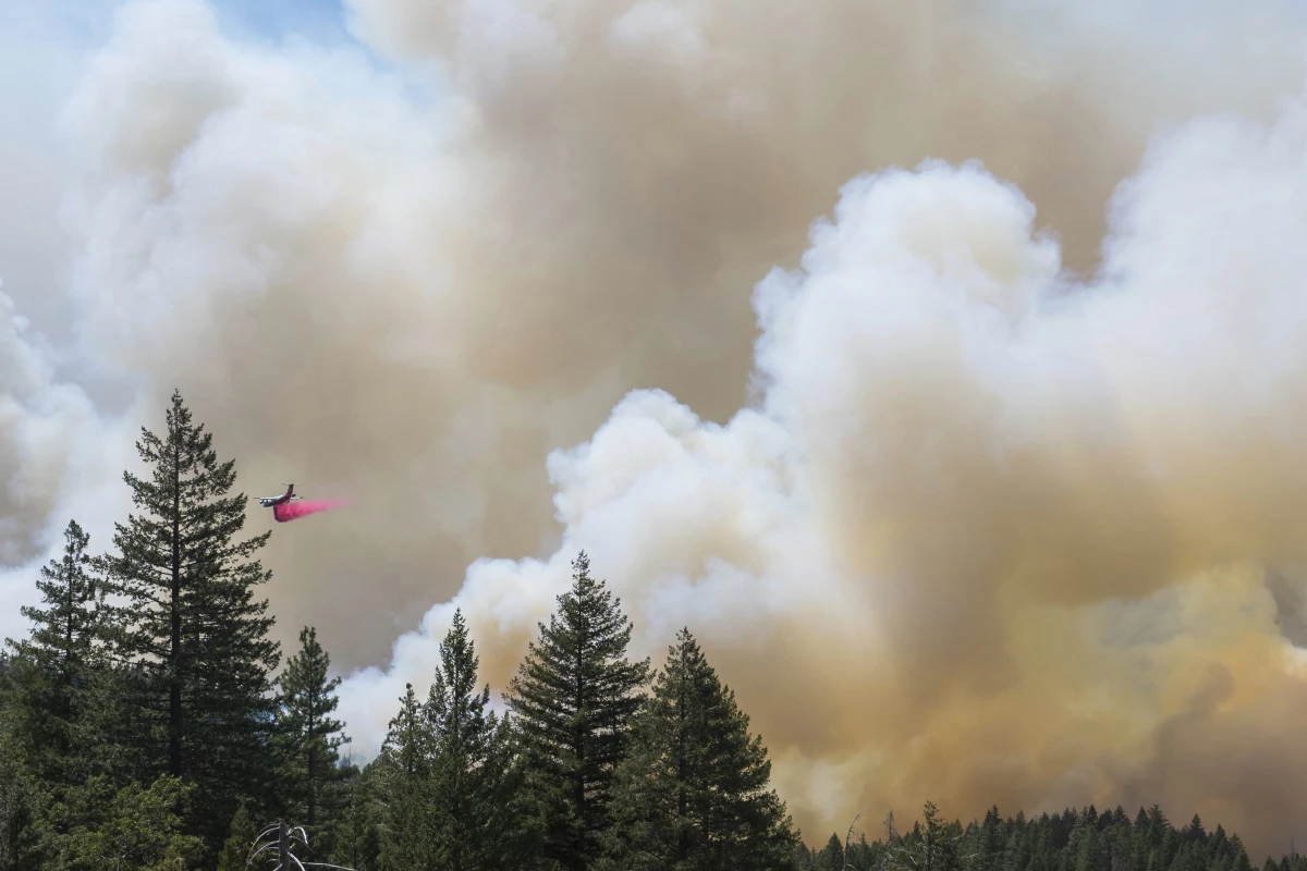 A plane drops fire retardant on the Park Fire near Forest Ranch, Calif., Sunday, July 28, 2024. Smoke from the fire is causing air quality issues across the Northwest and parts of Canada.