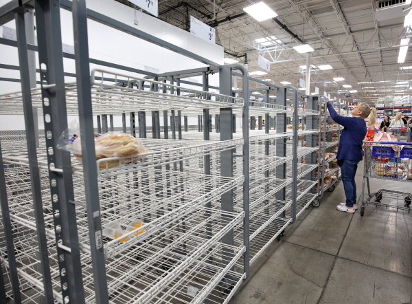Customers check mostly empty bread shelves at a shopping warehouse in Kissimmee, Fla., on Sunday.