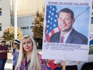 Stacey Augustson holds up a homemade sign during the protest outside U.S. Rep. David Valadao's district office in Bakersfield.