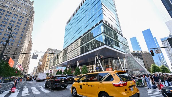A view outside Madison Square Garden from Seventh Avenue in New York with vehicles driving down the street. 