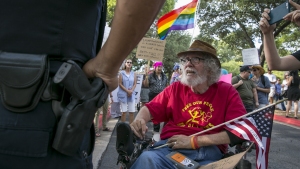 Bob Kafka, a disabled Vietnam veteran, talks with an Austin Police Officer as he and others try to enter a hotel property.
