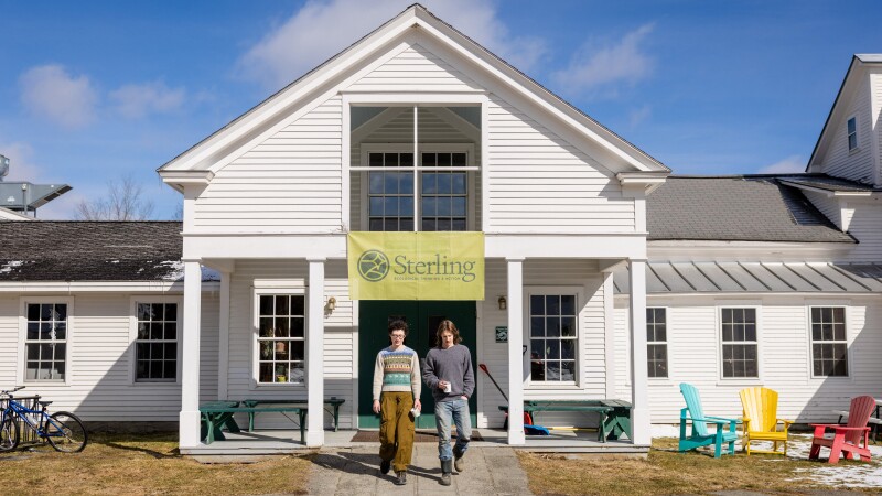 Izzy Johnson, left, and Jack Beatson are first-year students at Sterling College in Craftsbury Common, Vermont. The two students are walking out of the college building into the yard. 