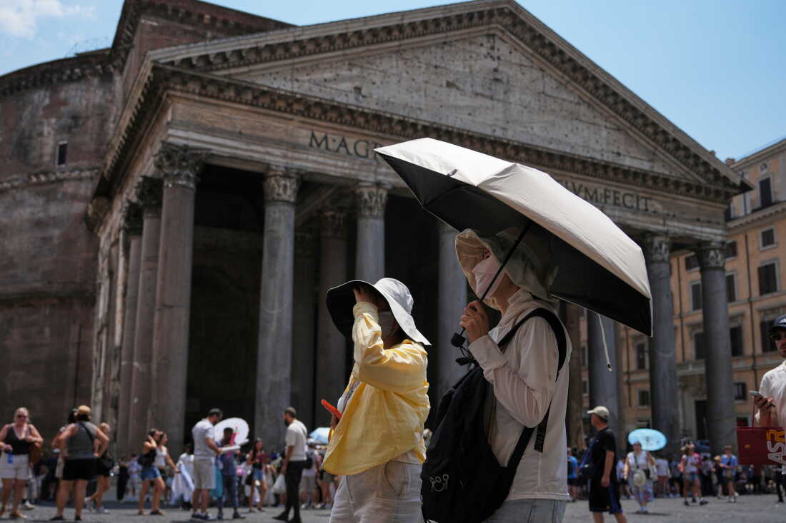 FILE - Tourists use umbrellas to take shelter from the sun in Pantheon Square in Rome, June 29, 2026.