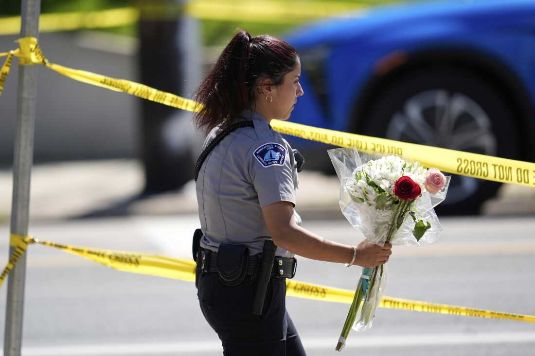 A police officer carries flowers outside the Annunciation Church's school after shooting on Wednesday in Minneapolis.