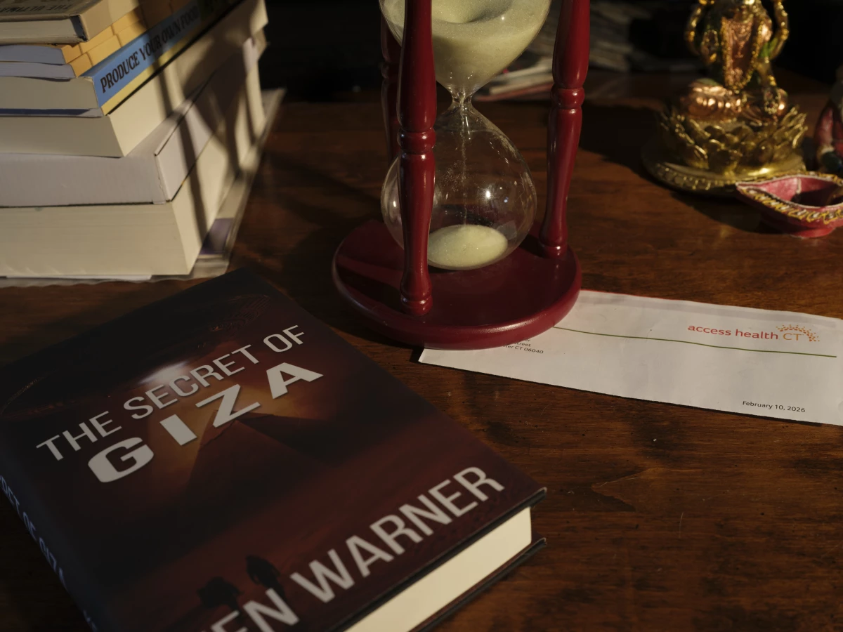 Ken Warner's novel, The Secret of Giza, is the first in a 10-volume series about twins who 'are thrust into a war that spans worlds,' according to the book description. There's an Access Health CT letter on the desk, too.