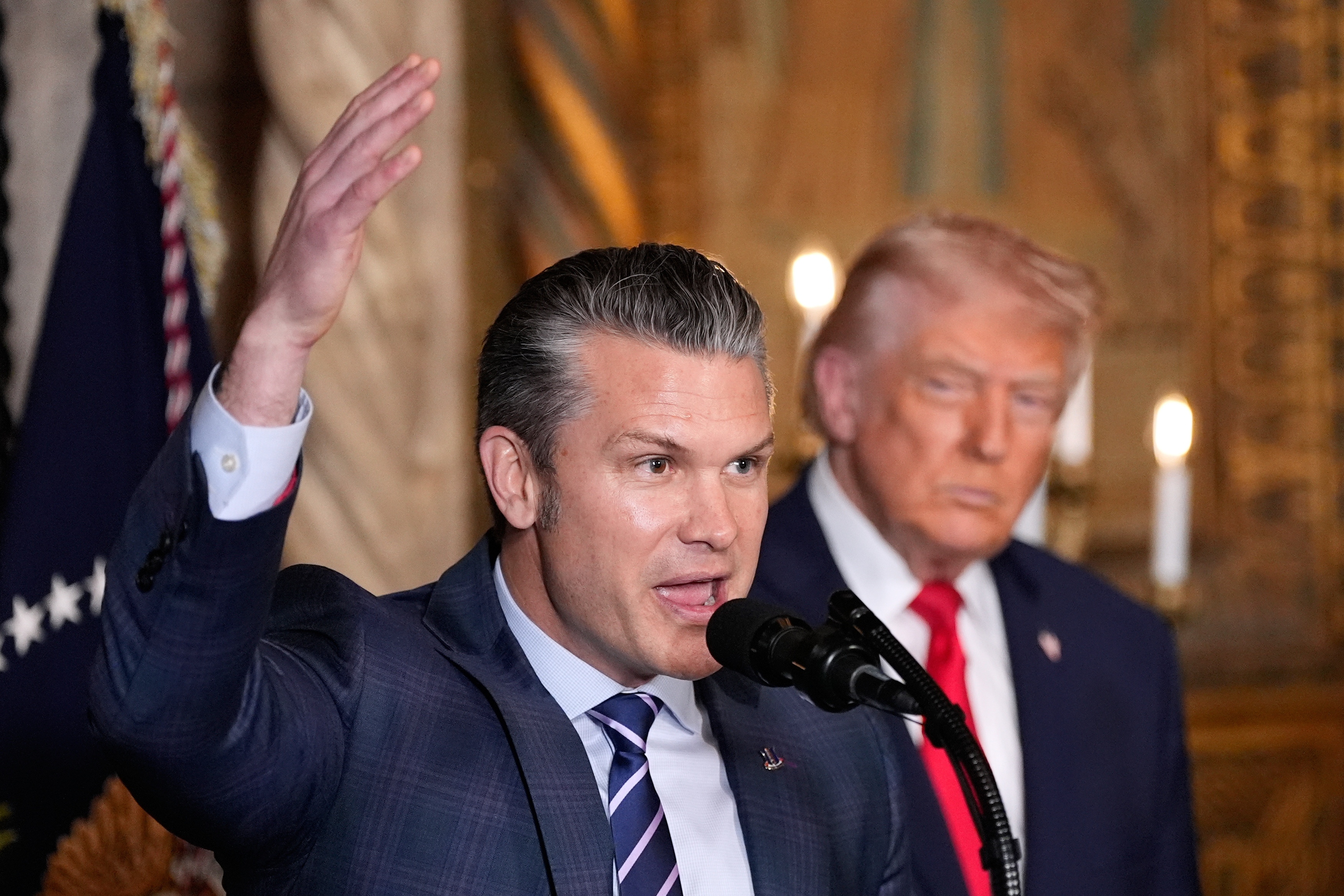 Defense Secretary Pete Hegseth speaks as President Donald Trump looks on, at Trump