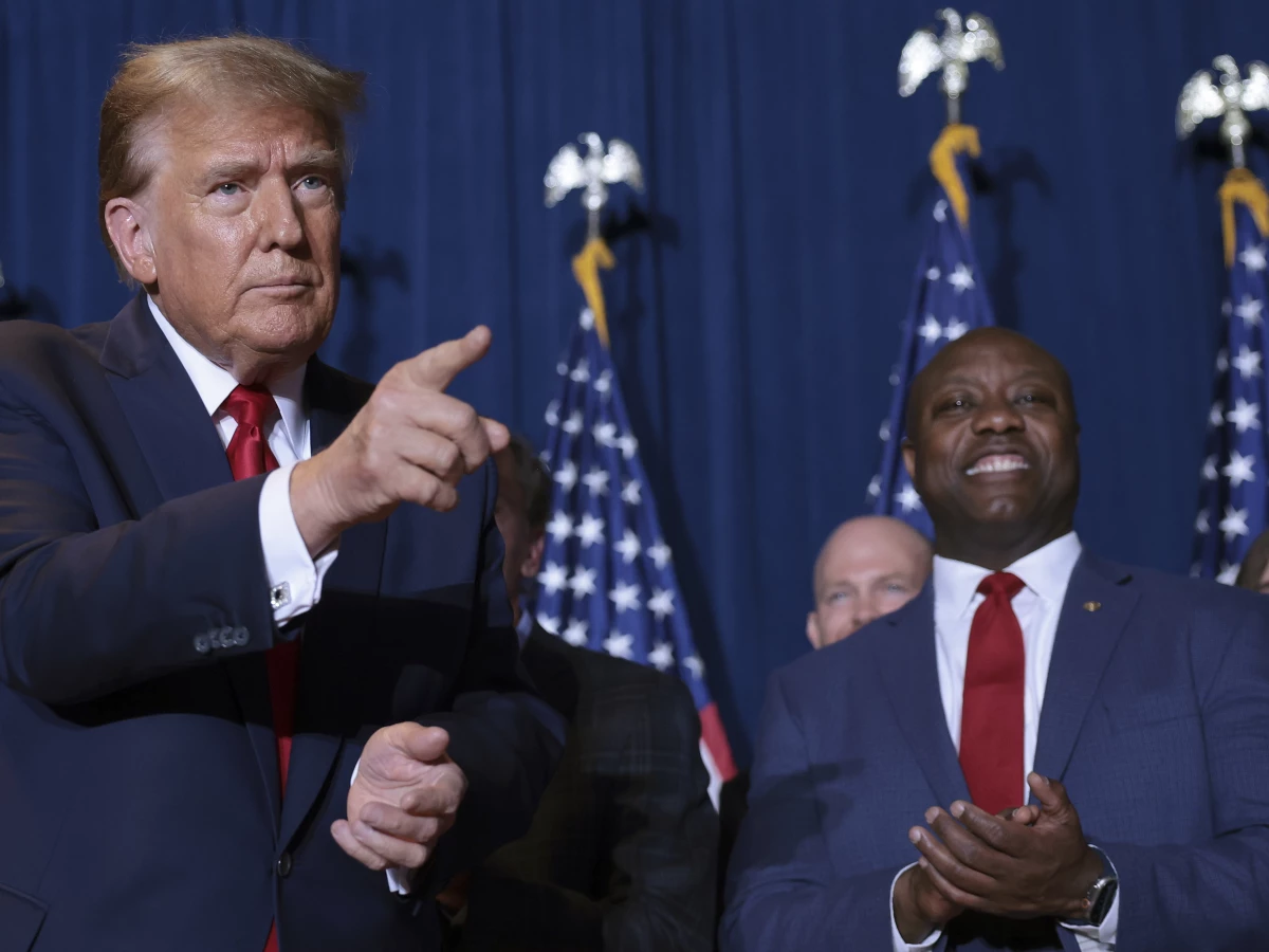 Republican presidential candidate and former President Donald Trump gestures to supporters as Sen. Tim Scott (R-SC) looks on during an election night watch party at the State Fairgrounds on February 24 in Columbia, S.C.