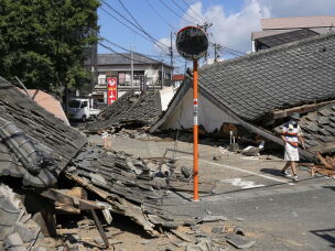 A person walks past the houses collapsed in an earthquake in Yatsushiro, Kumamoto Prefecture, southern Japan, Friday, July 31, 2026.