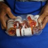 A person holds a plastic bag filled with prescription pill bottles. 