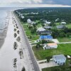 An aerial view of rebuilt elevated homes with green lawns along the sandy Waveland Beach in Mississippi, an area hard-hit by Hurricane Katrina 20 years ago.