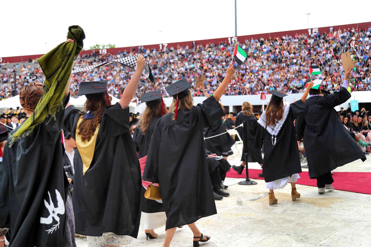 Pro-Palestinian students hold up Palestinian flags during UMass Amherst graduation ceremonies in May 2024. They left the graduation event in protest.