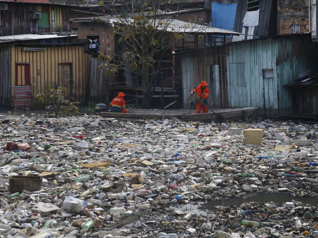 Workers remove garbage floating on the Negro River in Manaus, Brazil.
