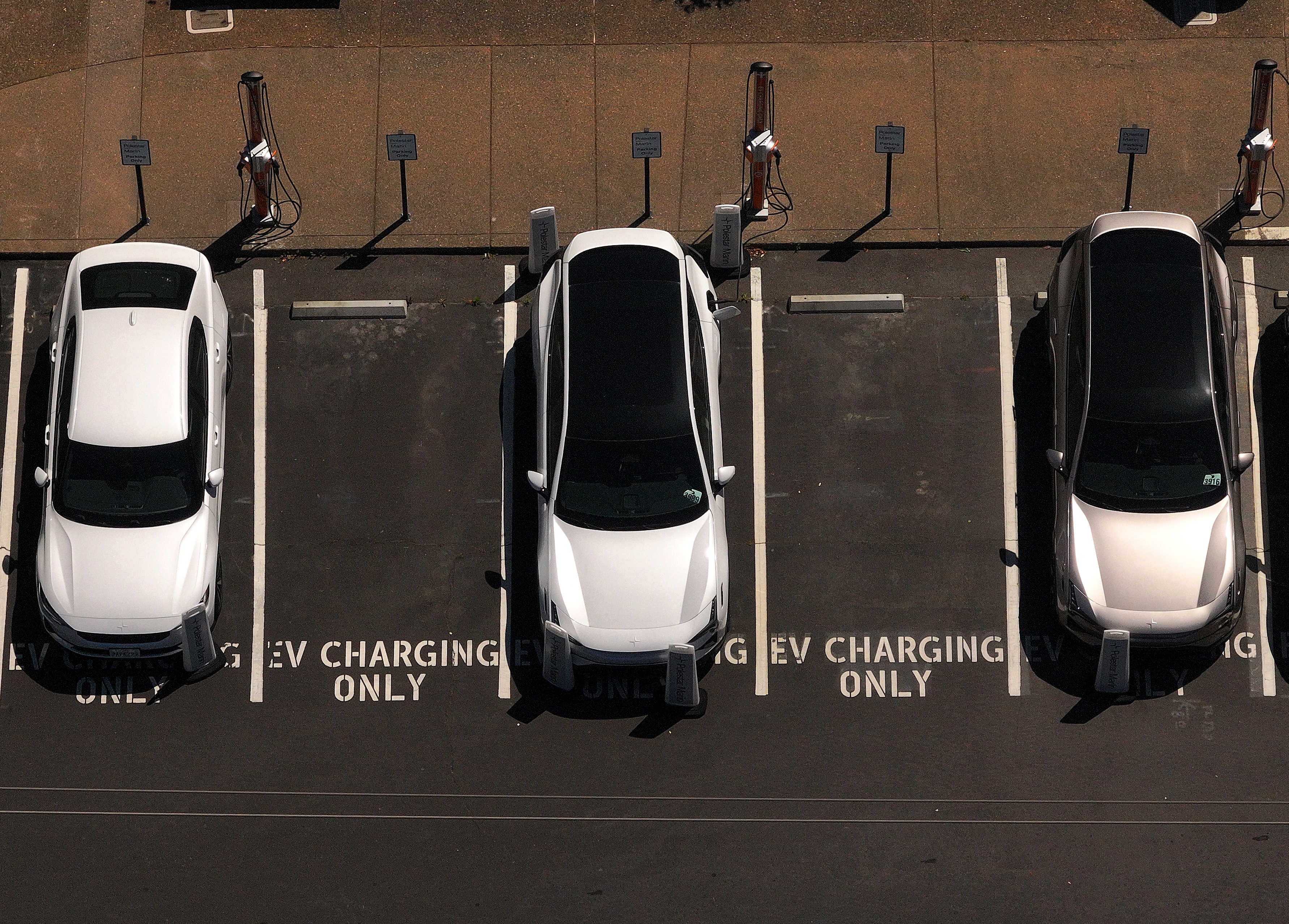 Electric cars sit parked at a charging station in Corte Madera, Calif., in May 2025.