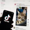 "Brain rot" is the term of the year for 2024, referring to concerns that endlessly scrolling through social media videos and other content can cause harm. Here, TikTok's logo is seen on a mobile phone in front of a computer screen showing a TikTok home screen. (AP Photo/Michael Dwyer, File)