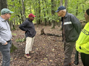 The Spears family gathers with Marc Schindler (left) around the cinder blocks marking children's graves near the former House of Reformation and Instruction for Colored Children in Cheltenham, Md.