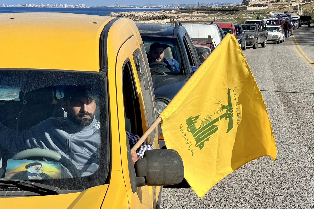 A man carries the Hezbollah flag and drives a car with a photo of the militant group's former leader, Hassan Nasrallah, on the windshield, as Lebanese citizens return to their homes after Israeli forces withdraw from the area in An-Naqoura, Lebanon, on Thursday.