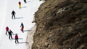 Skiers ski past dry ground at a ski resort in 2015 in Olympic Valley, Calif. The resort changed its name in 2021 and has been among the places removing a derogatory word from their names.