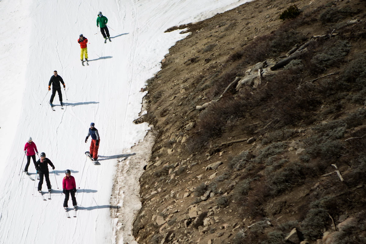 Skiers ski past dry ground at a ski resort in 2015 in Olympic Valley, Calif. The resort changed its name in 2021 and has been among the places removing a derogatory word from their names.