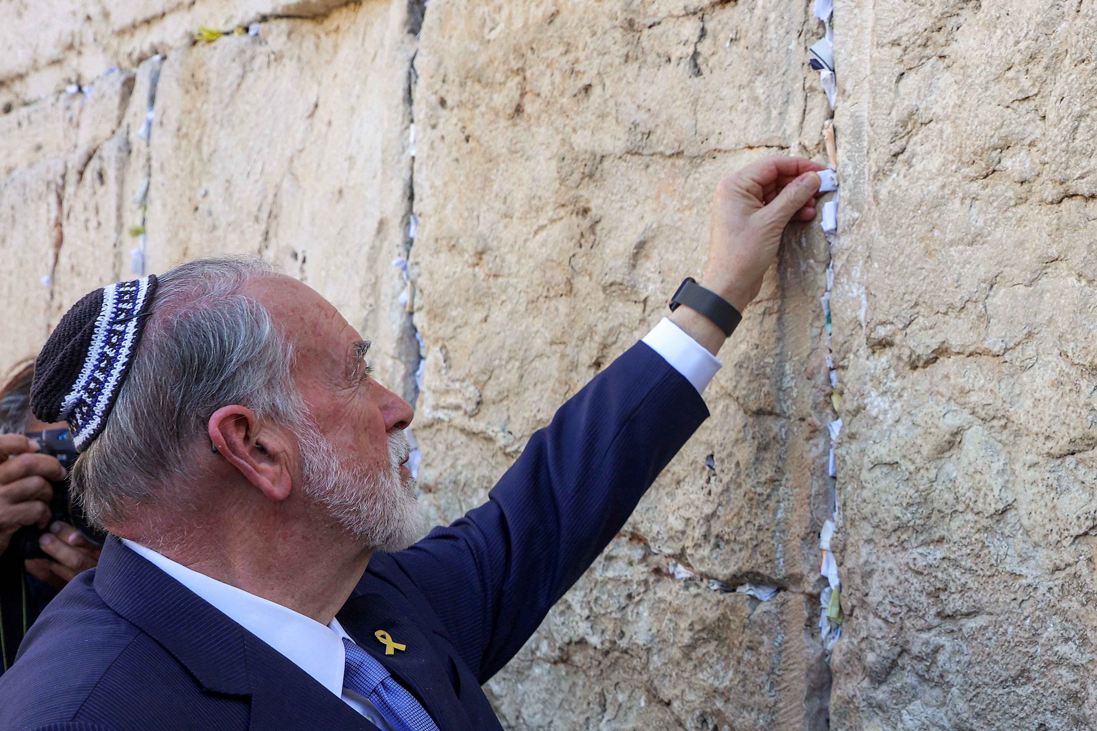Mike Huckabee, recently confirmed as U.S. ambassador to Israel, places a note given to him from President Trump in the cracks of the Western Wall, during Huckabee