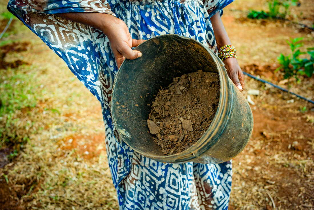 Kanangwa Newlove, the founder of Loctaguna Organics, holds a bucket of bokashi fertilizer.