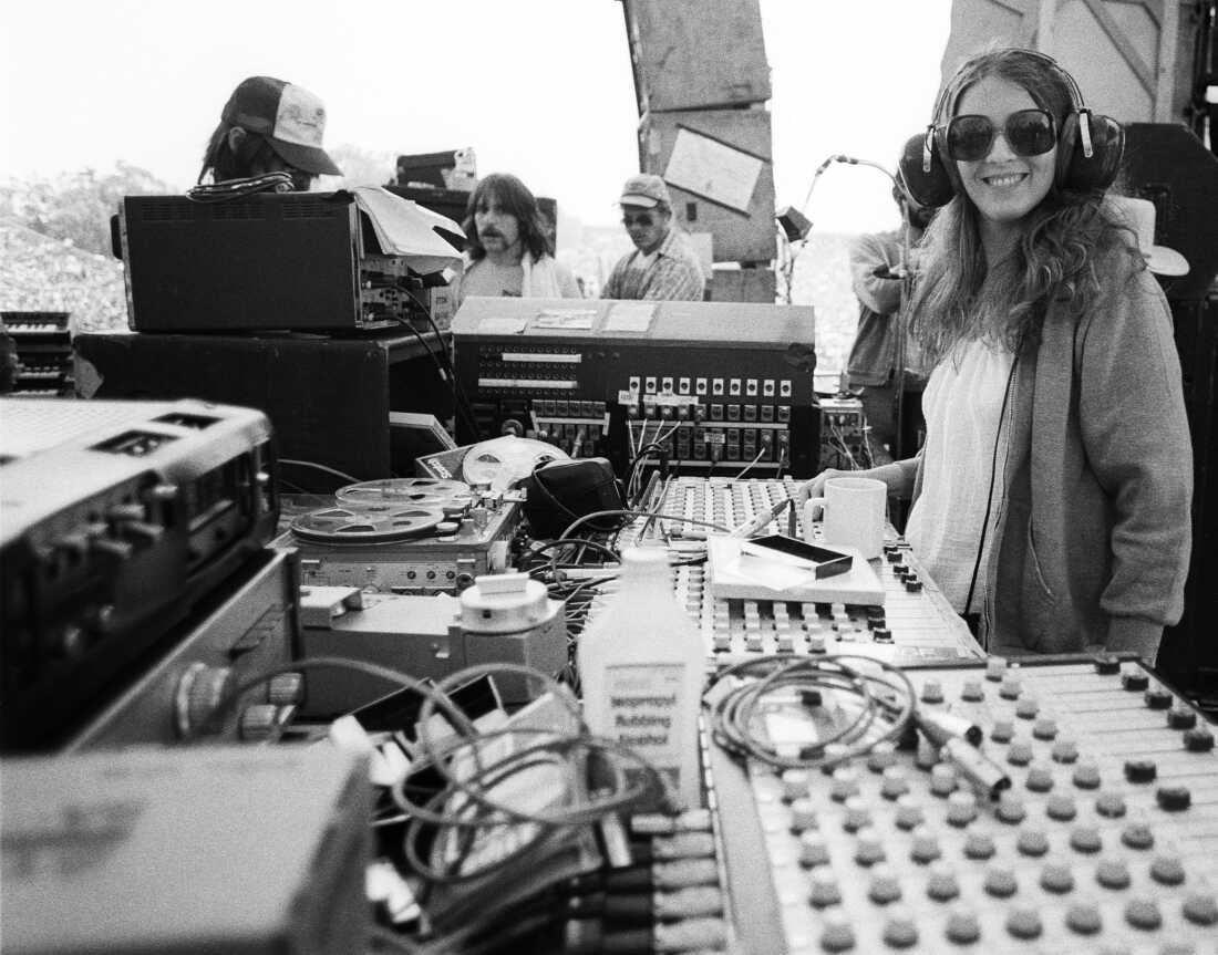 In this 1978 black-and-white photo, Betty Cantor-Jackson stands with sound engineering equipment. She's wearing headphones and sunglasses.