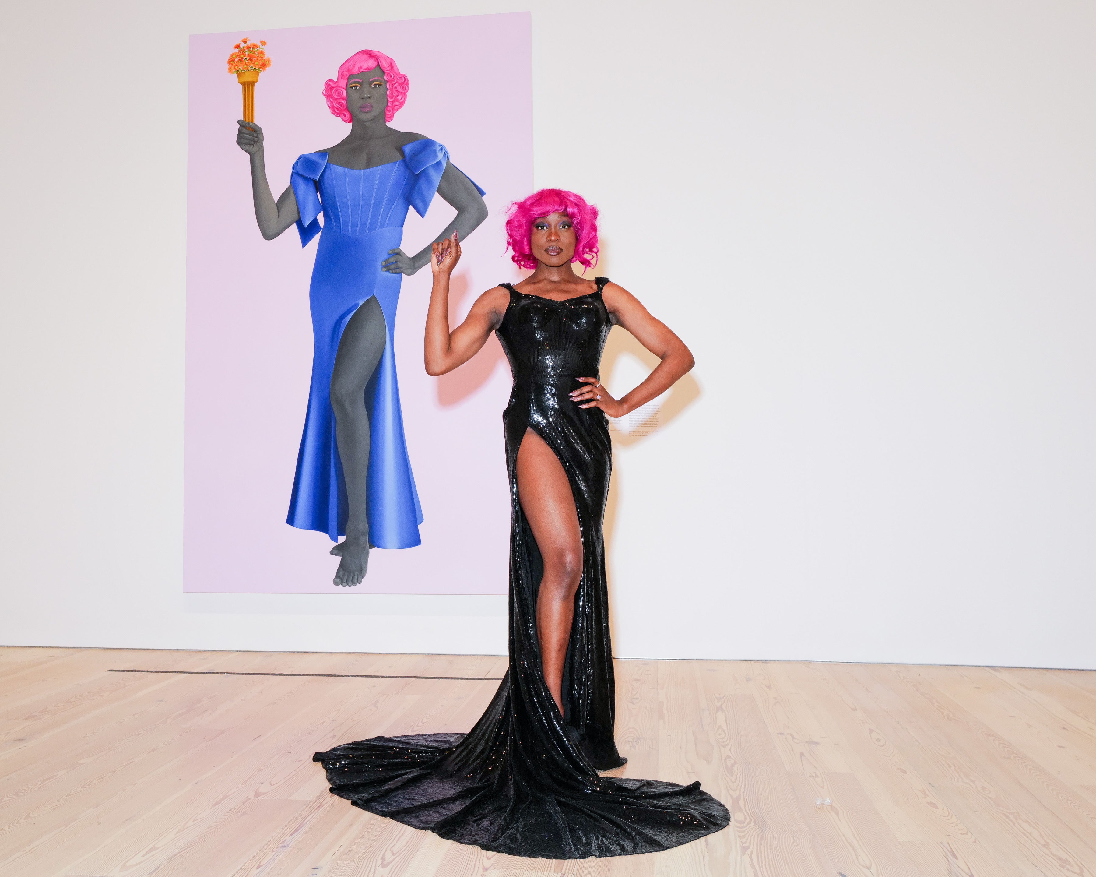 Arewà Basit poses in front of <em>Trans Forming Liberty </em>(2024), a 10-foot oil painting by Amy Sherald for which she served as the model.
