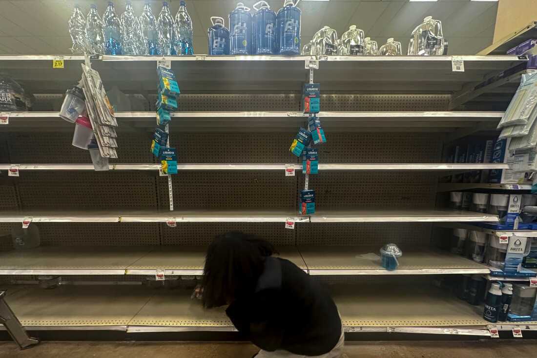 A shopper searches for water on near-empty shelves in a grocery store ahead of winter weather, Wednesday, in Marietta, Ga.