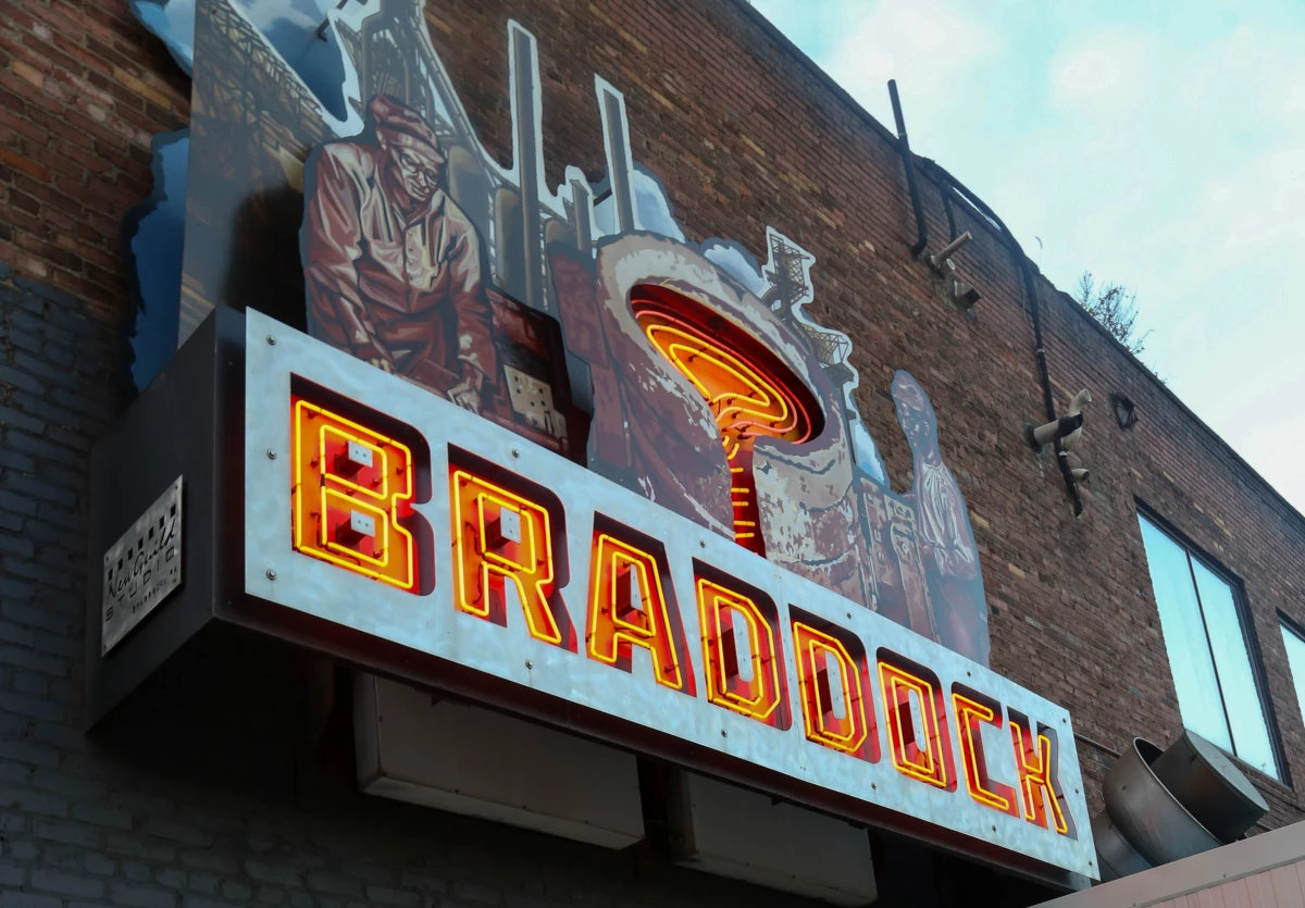 A neon sign paying homage to Braddock's steel working history flashes and hangs on the side of Braddock Public House on Oct. 16, 2024.