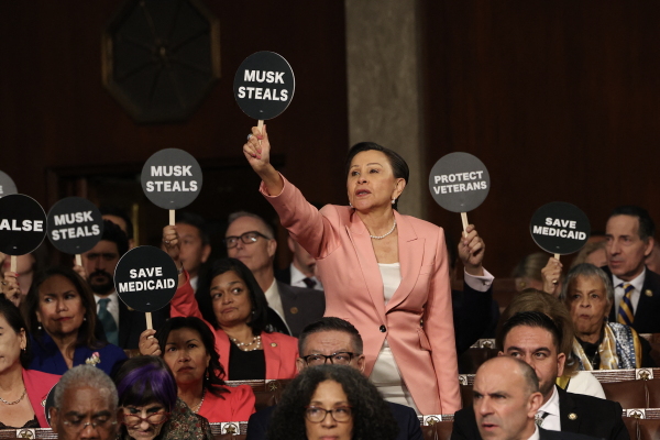 U.S. Rep. Nydia Velázquez, D-N.Y., holds a "Musk Steals" protest sign with fellow Democrats as Trump speaks during his address to Congress.