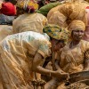 Women wearing plastic protective garments sift gold-bearing sediments at the Maidede mine in Mongbwalu, Ituri province, Democratic Republic of Congo, on June 16, 2026. Much of their clothing and bodies are covered in light brown sediment.