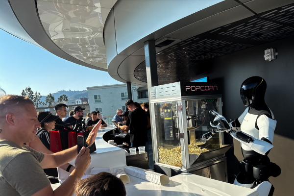 A Tesla Optimus robot scoops popcorn and gestures at attendees during the opening of the Tesla Diner and Drive-In restaurant and Supercharger in Los Angeles, Calif., on July 21, 2025.