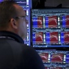 A trader stands in front of screens with charts displayed on the floor of the New York Stock Exchange.