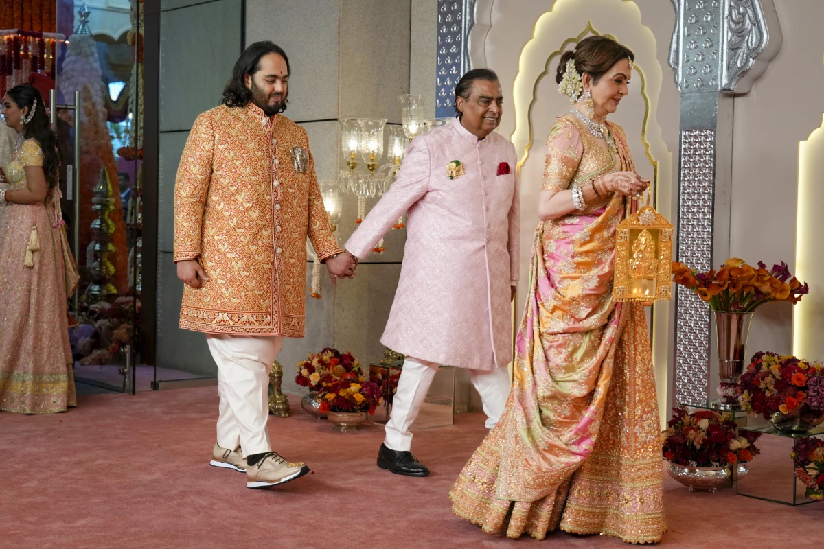 Billionaire Mukesh Ambani (center) takes his son Anant Ambani by the hand as they walk with Nita Ambani (right) at the wedding in Mumbai on Friday.