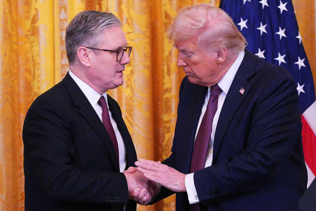 U.K. Prime Minister Keir Starmer, on the left side of the frame, and President Trump, on the right side of the frame, shake hands at a news conference at the White House on February 27, 2025. Behind them is a gold curtain and a U.S. flag.