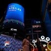 People walk past a screen showing the CSI 300 Index at a shopping mall in Guangzhou, in southern China's Guangdong province.