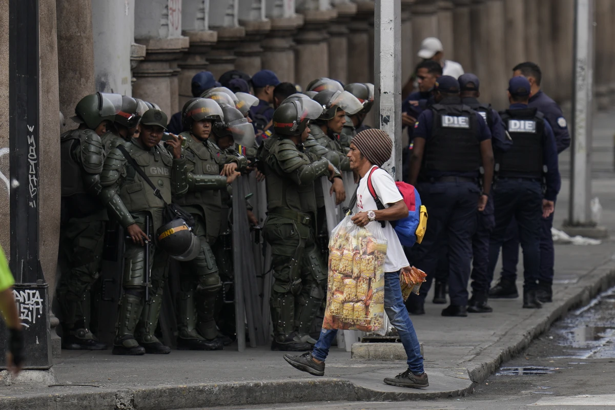 A street vendor walks by members of the Bolivarian National Guard ahead of President Nicolas Maduro's swearing-in for a third term, in Caracas, Venezuela.