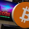 A bitcoin logo is displayed at a conference in Hong Kong on Aug. 28, 2025. Bitcoin and other cryptocurrencies soared this year — until crashing in October.