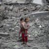 A Palestinian girl carries a child through the rubble of houses destroyed by Israeli bombardment in Gaza City on March 3, 2024, amid the ongoing conflict between Israel and the Hamas movement.