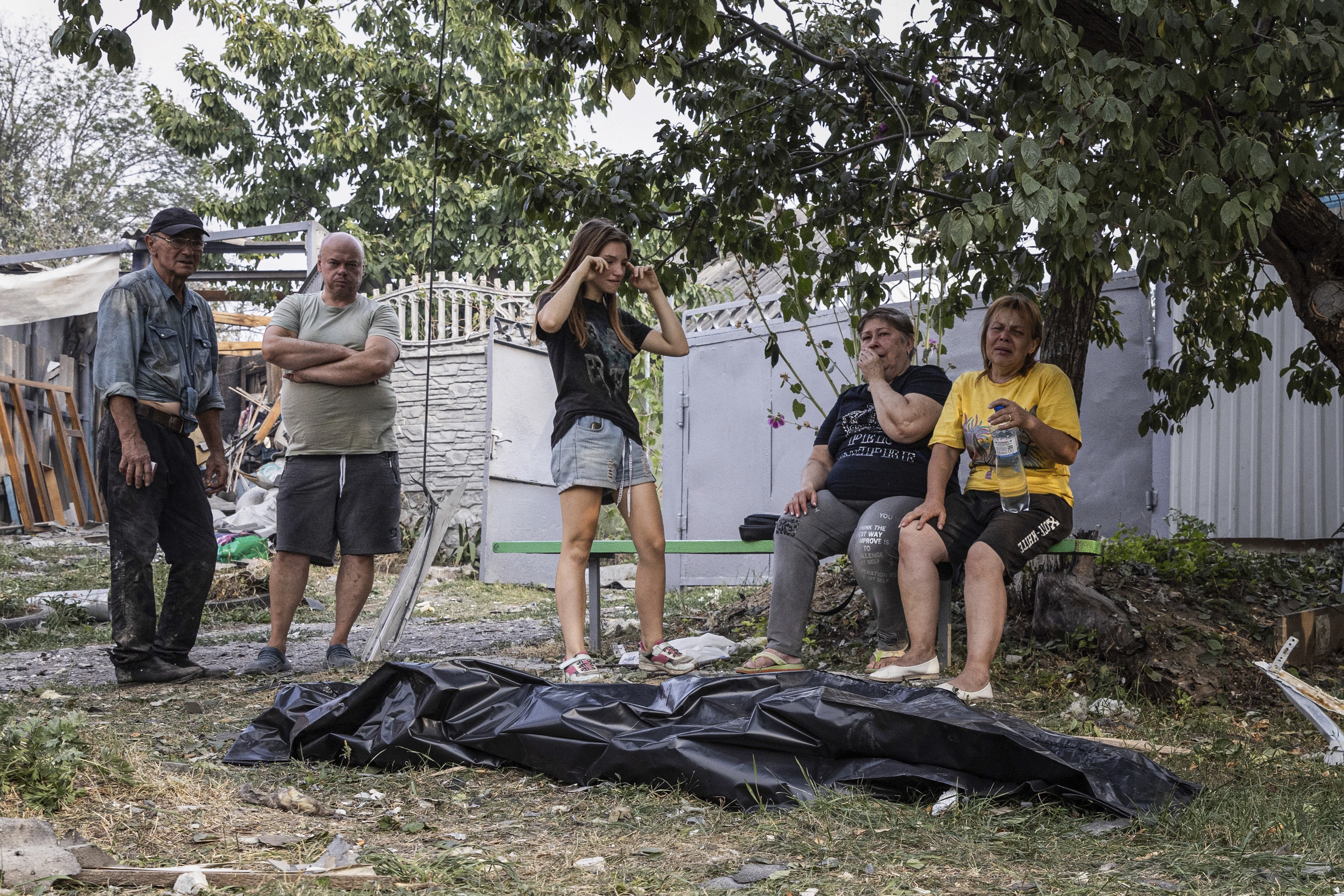 People cry near the body of a relative who was killed in a Russian strike on the residential neighbourhood in Cherkaska Lozova, Kharkiv region, Ukraine, Saturday Aug. 31. 2024.