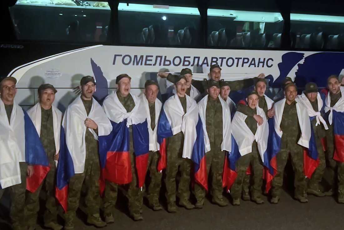 In this photo taken from video distributed by Russian Defense Ministry Press Service on Wednesday, Russian servicemen pose with national flags at an exchange area in Belarus after returning from captivity during a POWs exchange of a group of servicemen between Russia and Ukraine.