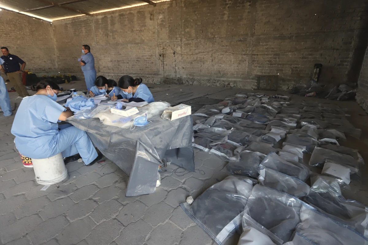 This photo released by the Jalisco State Attorney General's Office shows investigators classifying objects found at the Izaguirre Ranch, where skeletal remains were discovered, in the municipality of Teuchitlan, Mexico on Tuesday.