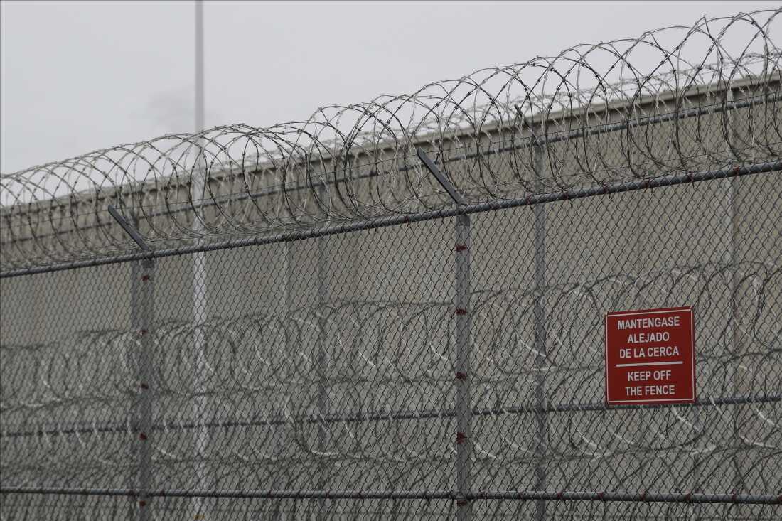 FILE - Barbed wire fencing is shown behind a sign in English and Spanish in a recreation yard used by detainees during a media tour of the U.S. Immigration and Customs Enforcement detention center, Dec. 16, 2019, in Tacoma, Wash.
